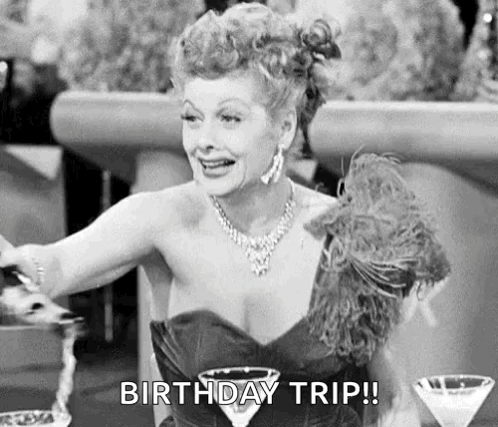 A Black And White Photo Of A Woman Sitting At A Table With A Martini Glass And A Birthday Trip ! GIF