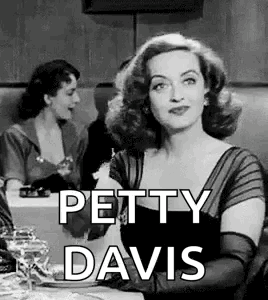 A Black And White Photo Of A Woman Sitting At A Table With The Words `` Petty Davis '' . GIF