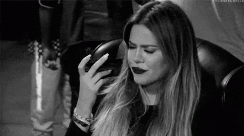 A Black And White Photo Of A Woman Sitting In A Chair With Her Hand On Her Face . GIF