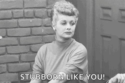 A Black And White Photo Of A Woman Sitting In Front Of A Brick Wall Saying `` Stubborn Like You '' . GIF
