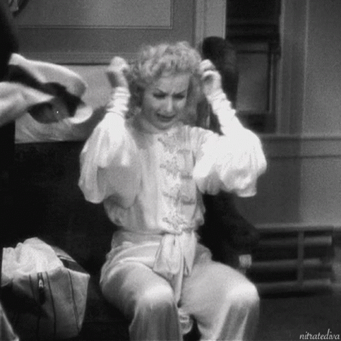 A Black And White Photo Of A Woman Sitting On A Chair With The Caption Nitratediva GIF