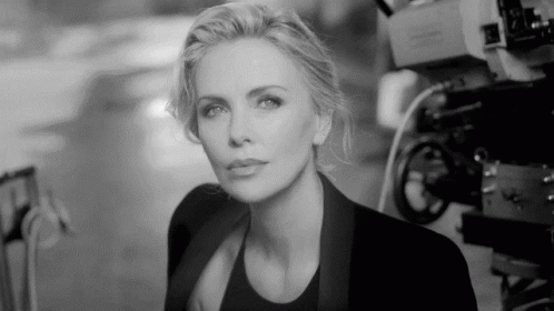 A Black And White Photo Of A Woman Standing In Front Of Cameras GIF