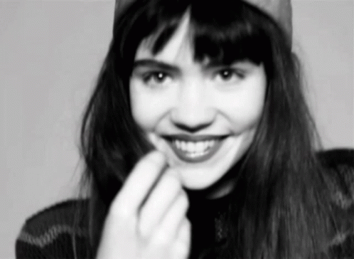 A Black And White Photo Of A Woman Wearing A Hat And Smiling . GIF