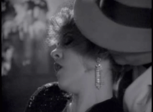 A Black And White Photo Of A Woman Wearing A Hat GIF