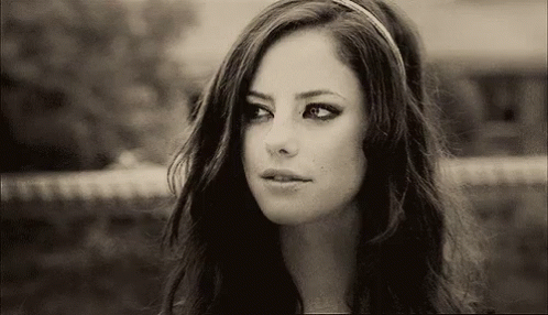 A Black And White Photo Of A Woman Wearing A Headband And Looking At The Camera . GIF