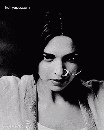 A Black And White Photo Of A Woman Wearing A Nose Ring And A Pearl Necklace . GIF