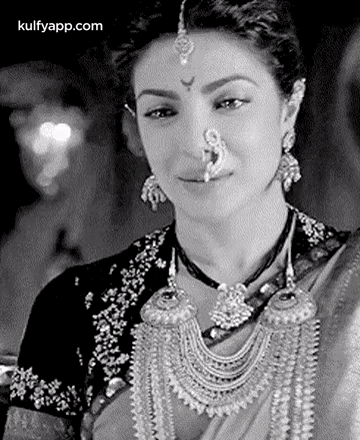 A Black And White Photo Of A Woman Wearing A Nose Ring And Earrings . GIF