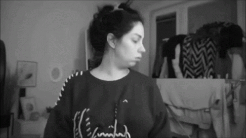 A Black And White Photo Of A Woman Wearing A Sweater That Says ' I 'M Tired ' On It . GIF