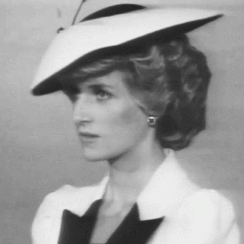 A Black And White Photo Of A Woman Wearing A White Hat And Earrings GIF