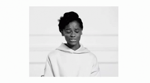 A Black And White Photo Of A Woman Wearing A White Hoodie And Looking At The Camera . GIF