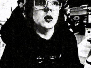 A Black And White Photo Of A Woman Wearing Glasses And A Hat GIF