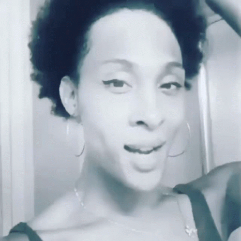 A Black And White Photo Of A Woman Wearing Hoop Earrings And A Necklace GIF