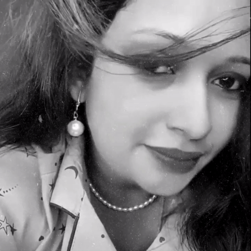 A Black And White Photo Of A Woman Wearing Pearl Earrings And A Pearl Necklace GIF