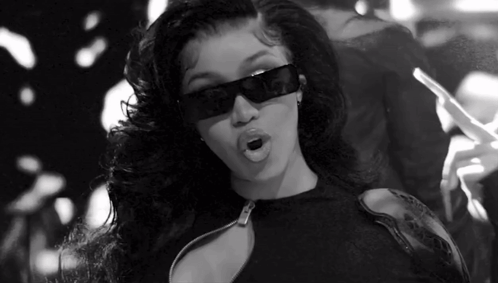 A Black And White Photo Of A Woman Wearing Sunglasses And Holding A Cigarette . GIF
