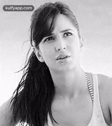 A Black And White Photo Of A Woman With A Ponytail Making A Funny Face . GIF