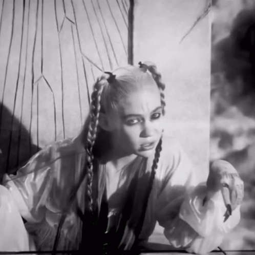 A Black And White Photo Of A Woman With Braids On Her Hair GIF