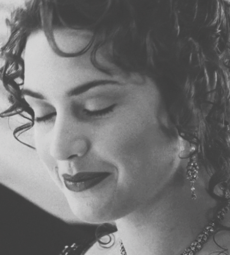 A Black And White Photo Of A Woman With Curly Hair And Earrings GIF