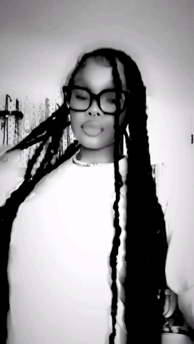 A Black And White Photo Of A Woman With Long Braids Wearing Glasses And A Nose Ring . GIF