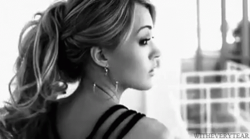 A Black And White Photo Of A Woman With Long Hair In A Ponytail . GIF