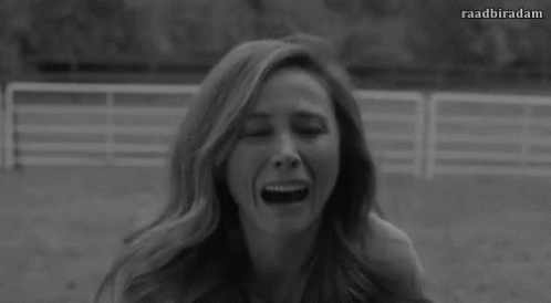A Black And White Photo Of A Woman With Long Hair Sitting In A Field . GIF