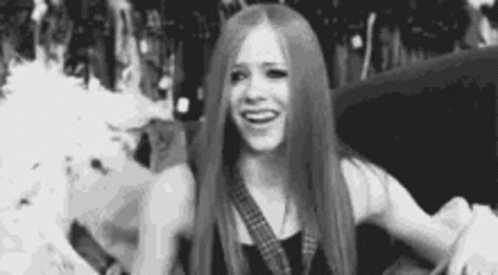 A Black And White Photo Of A Woman With Long Hair Smiling . GIF