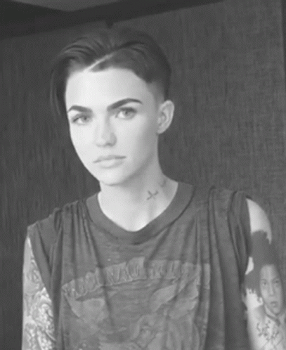 A Black And White Photo Of A Woman With Short Hair And A Tattoo On Her Neck GIF