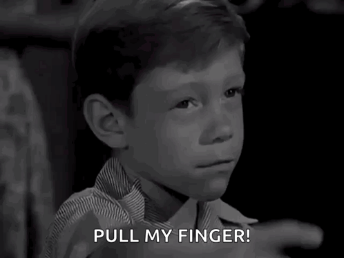 A Black And White Photo Of A Young Boy Pointing With The Words Pull My Finger Below Him GIF