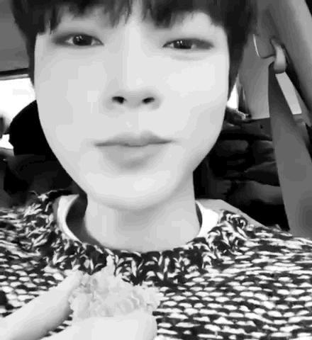 A Black And White Photo Of A Young Boy Sitting In A Car Eating A Sandwich . GIF