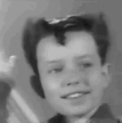 A Black And White Photo Of A Young Boy With A Mohawk Smiling . GIF