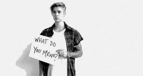 A Black And White Photo Of A Young Man Holding A Sign That Says `` What Do You Mean '' . GIF