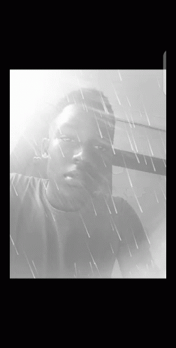 A Black And White Photo Of A Young Man In The Rain GIF