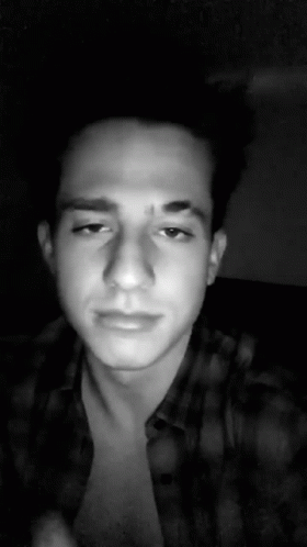 A Black And White Photo Of A Young Man Wearing A Plaid Shirt And Looking At The Camera . GIF