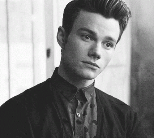 A Black And White Photo Of A Young Man Wearing A Polka Dot Shirt And Jacket . GIF