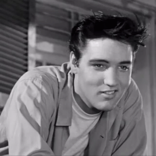 A Black And White Photo Of A Young Man With A Slight Smile On His Face GIF