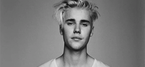 A Black And White Photo Of A Young Man With Blonde Hair And A White Shirt . GIF