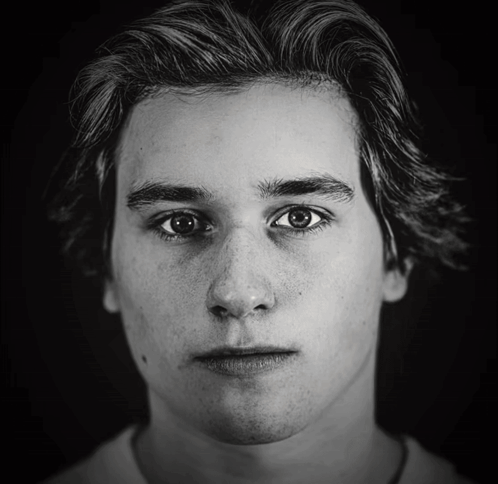 A Black And White Photo Of A Young Man With Freckles GIF