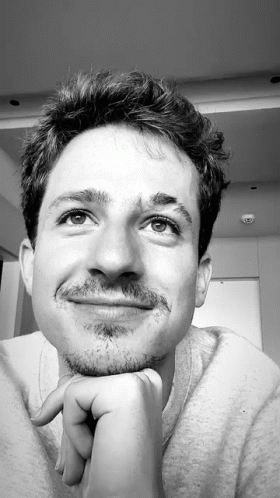 A Black And White Photo Of A Young Man With His Hand On His Chin GIF