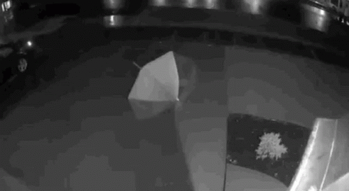 A Black And White Photo Of An Umbrella Floating On Top Of A Pool Of Water . GIF