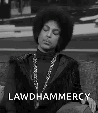 a black and white photo of prince sitting on a couch with his eyes closed and a chain around his neck .