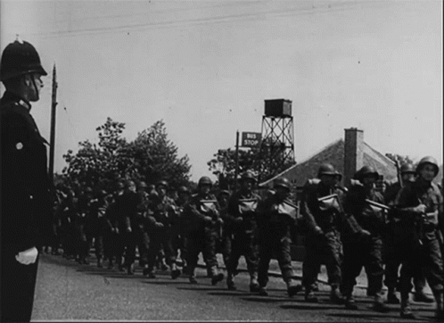 A Black And White Photo Of Soldiers Marching In Front Of A Sign That Says End Stop GIF
