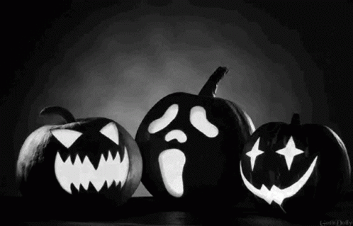 A Black And White Photo Of Three Carved Pumpkins With Faces On Them . GIF