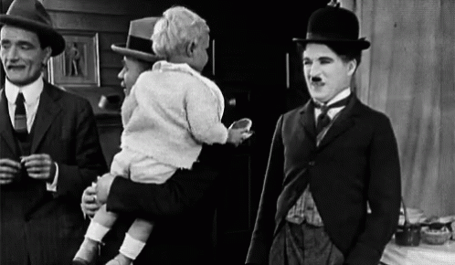 A Black And White Photo Of Three Men Standing Next To Each Other . One Of The Men Is Holding A Baby . GIF