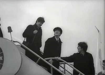 a black and white photo of three men walking up stairs .