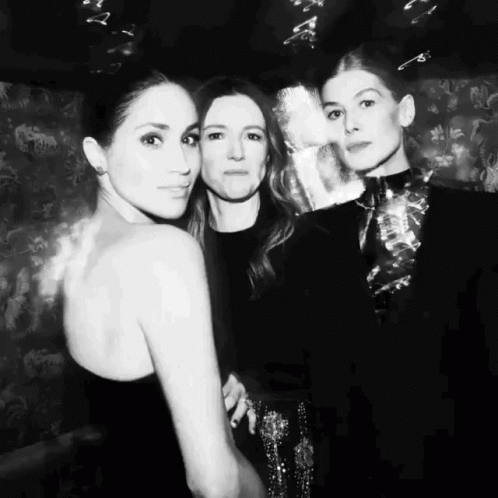 a black and white photo of three women posing for the camera