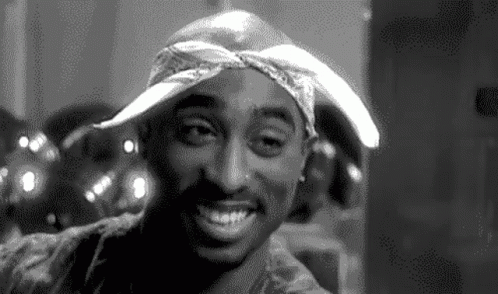 A Black And White Photo Of Tupac Shakur Smiling GIF