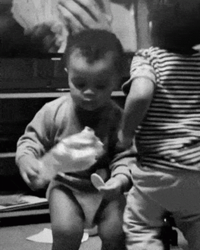 A Black And White Photo Of Two Babies Playing GIF