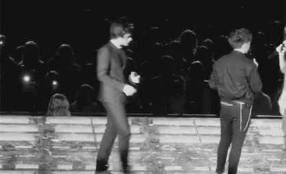 A Black And White Photo Of Two Men Dancing On A Stage . GIF