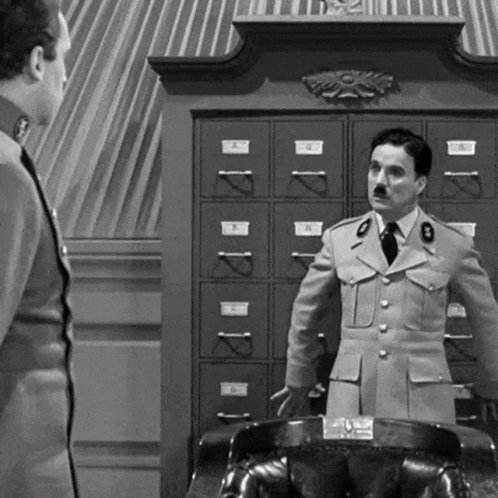 a black and white photo of two men in military uniforms standing next to each other in front of a filing cabinet .
