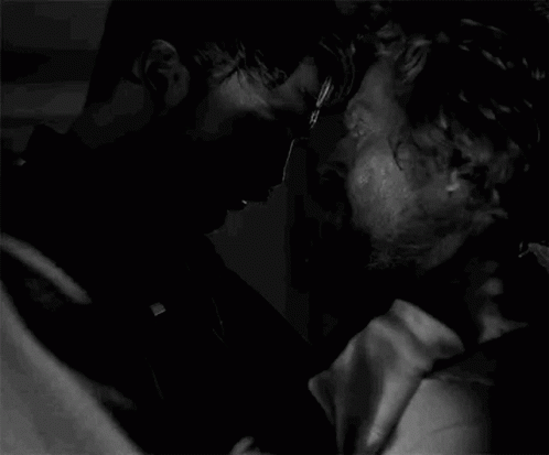 A Black And White Photo Of Two Men Kissing Each Other In A Dark Room . GIF