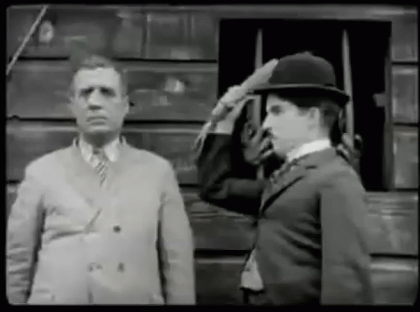 A Black And White Photo Of Two Men Saluting Each Other . GIF